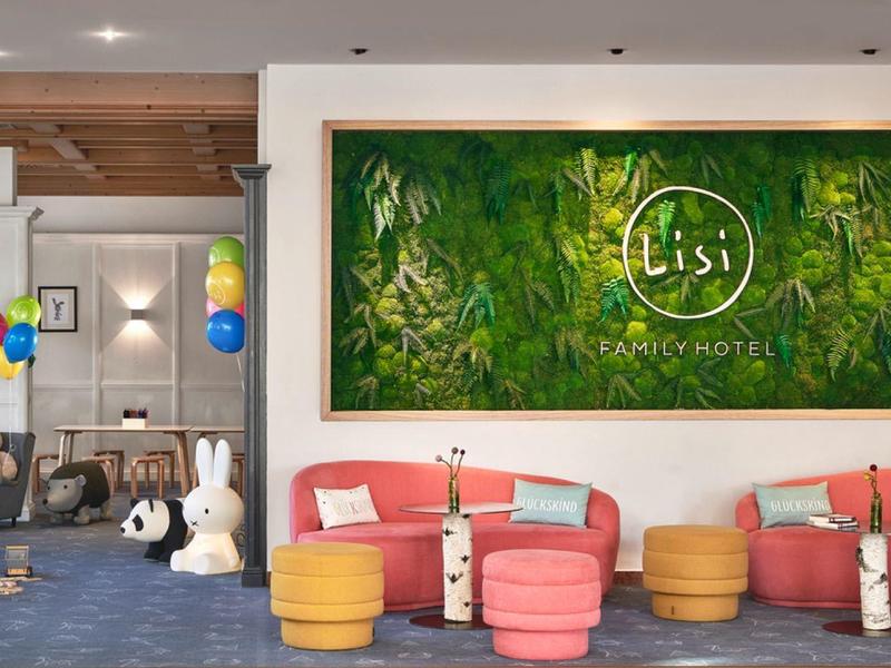 Área de descanso acogedora en hotel con sillones coloridos, pufs y decoración con globos y peluches grandes.