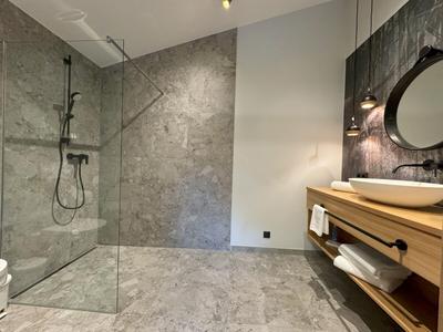Baño moderno con ducha a ras de suelo, azulejos grises y mueble de lavabo de madera