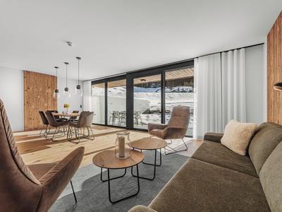 Sala de estar moderna con grandes ventanales con vistas a montañas nevadas.