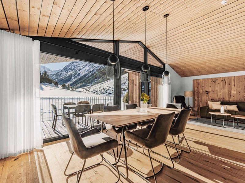 Moderne, lichte eetruimte met groot raam en uitzicht op bergen in een gezellig houten huis.