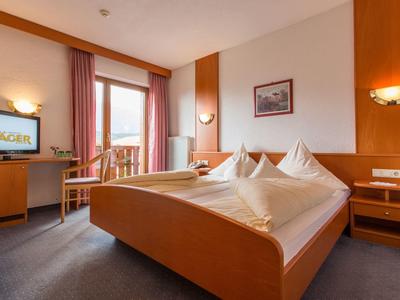 Przytulny pokój hotelowy z dużym łóżkiem, biurkiem i balkonem z widokiem na zewnątrz.