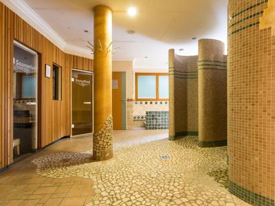 Jasna strefa wellness z mozaikową podłogą i okrągłymi kolumnami