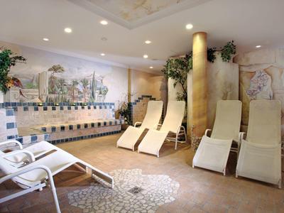 Strefa relaksu z leżakami i dekoracyjnym mozaikowym wzorem na ścianie w hotelowym spa.