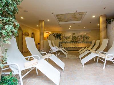 Pokój relaksacyjny z białymi leżakami i roślinami w strefie spa