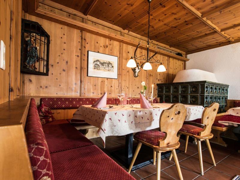 Przytulna jadalnia z drewnianymi ścianami, stołem, krzesłami i kaflowym piecem w tradycyjnym pokoju.