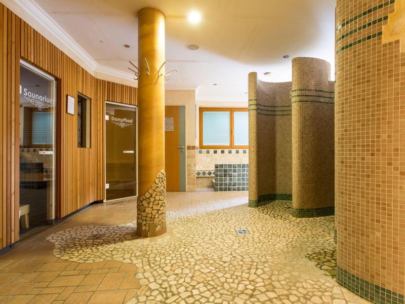 Jasna strefa wellness z mozaikową podłogą i okrągłymi kolumnami