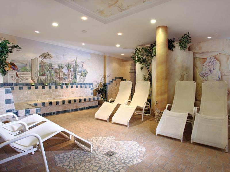 Strefa relaksu z leżakami i dekoracyjnym mozaikowym wzorem na ścianie w hotelowym spa.