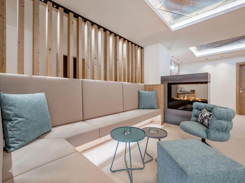 Modern gemeubileerde woonkamer met hoekbank, fauteuils en tafel in een hotelkamer.