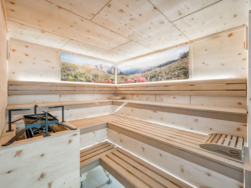 Lichte sauna met houten bekleding en panoramische afbeelding aan de muur.