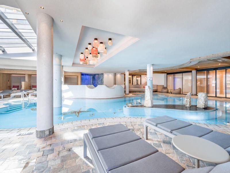Helder verlicht binnenzwembad met ligstoelen en modern design in een hotel.