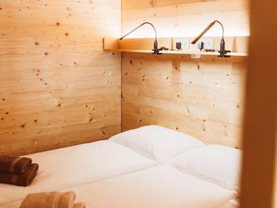 Cozy bedroom with light wood, two single beds, and two wall-mounted lamps.