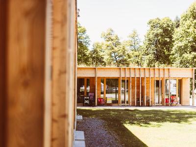 Modern wooden building with glass front and large lawn in sunny outdoor area