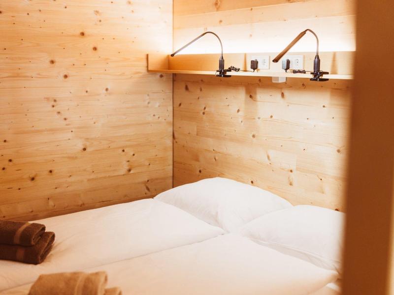 A cozy bedroom with two single beds and wooden paneled walls.