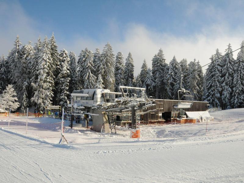 Ski lift station in a snowy winter landscape with snow-covered trees in the background.