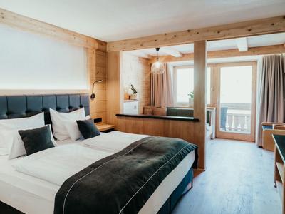 Bright hotel room with large bed, wooden decor, and balcony
