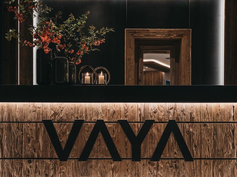 Elegant hotel lobby with illuminated logo, wooden wall, and flower arrangement