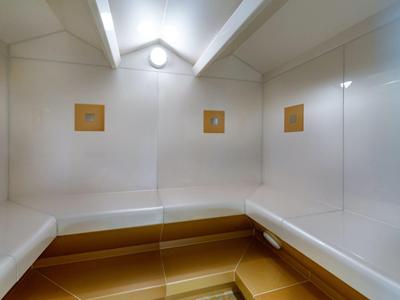 Bright, modern sauna with white walls and wooden benches along the walls.