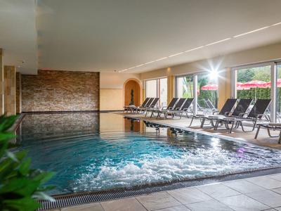 Modern indoor pool with lounge chairs and jacuzzi in a hotel