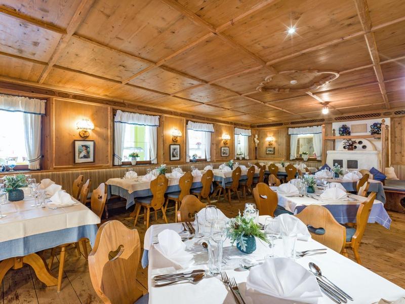 Rustic dining room with wooden furniture and tables set with white tablecloths.