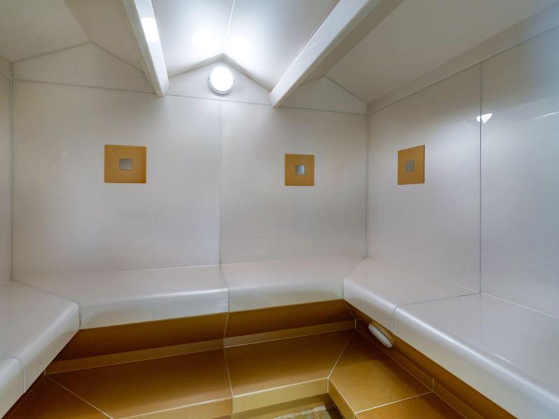 Bright, modern sauna with white walls and wooden benches along the walls.