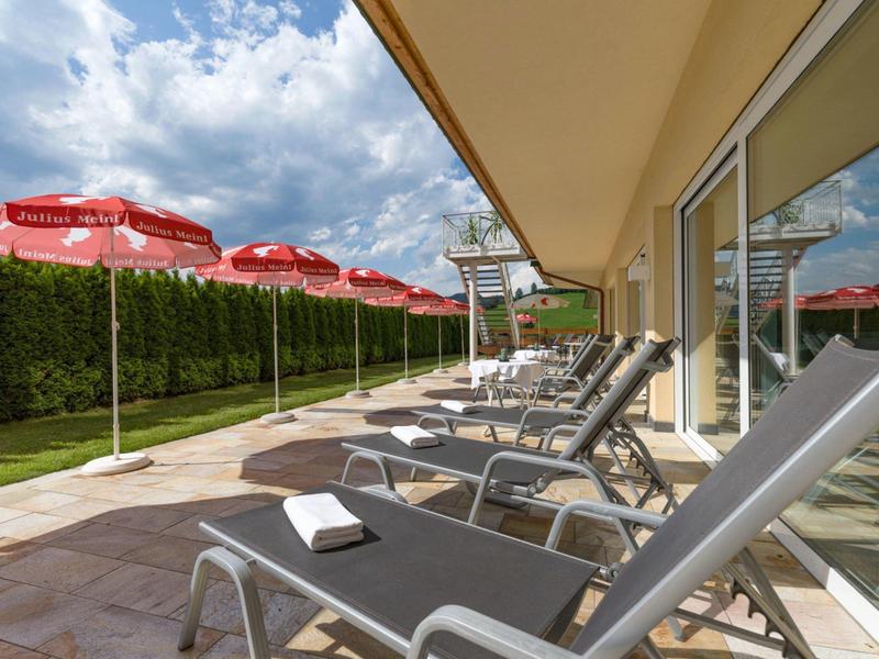 Terrace with lounge chairs and umbrellas next to a hotel building