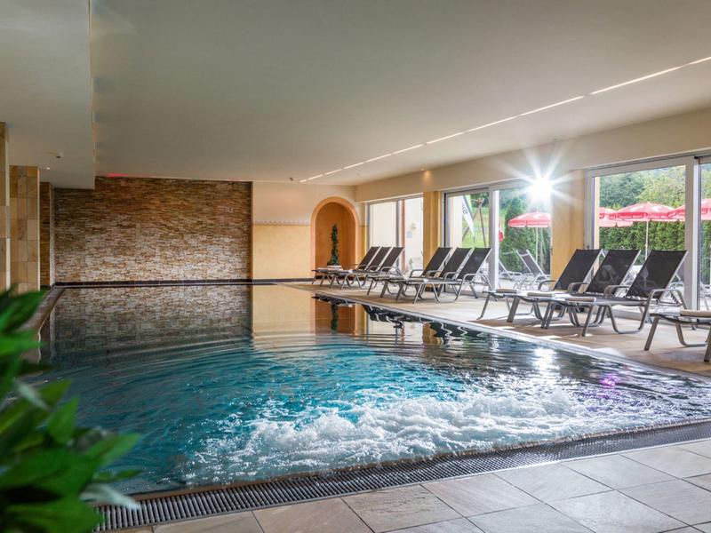 Modern indoor pool with lounge chairs and jacuzzi in a hotel