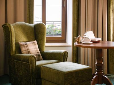 Poltrona verde accogliente con poggiapiedi e tavolo di legno vicino alla finestra in una camera d'hotel.