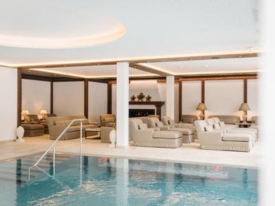 Piscina coperta moderna con aree salotto confortevoli e illuminazione calda in un hotel.