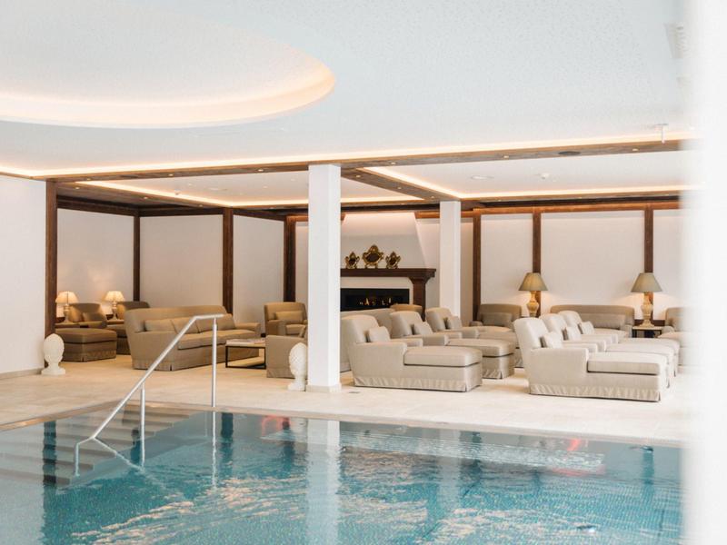 Piscina coperta moderna con aree salotto confortevoli e illuminazione calda in un hotel.