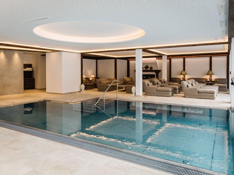 Piscina interna moderna con aree lounge e illuminazione elegante in un hotel.