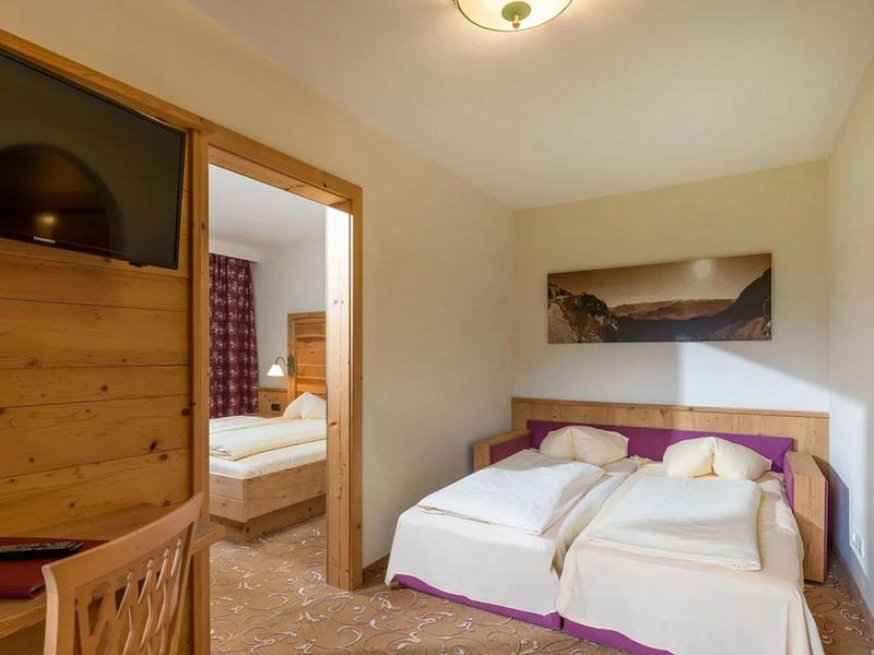 Hotelkamer met twee eenpersoonsbedden, houten meubels en een landschapsfoto aan de muur.