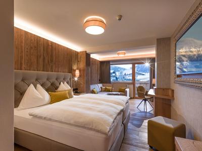 Moderne hotelkamer met tweepersoonsbed, zithoek en groot raam met berguitzicht.