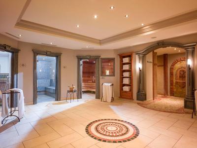 Corridoio d'hotel luminoso con pavimento a mosaico, più porte e illuminazione moderna.