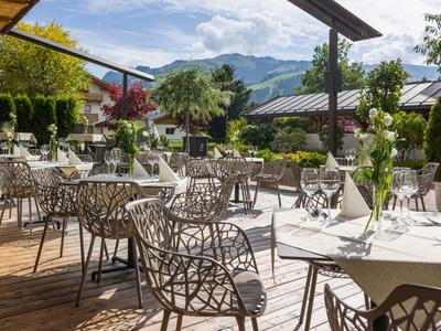 Buitenrestaurant met gedekte tafels en uitzicht op bergen onder blauwe lucht