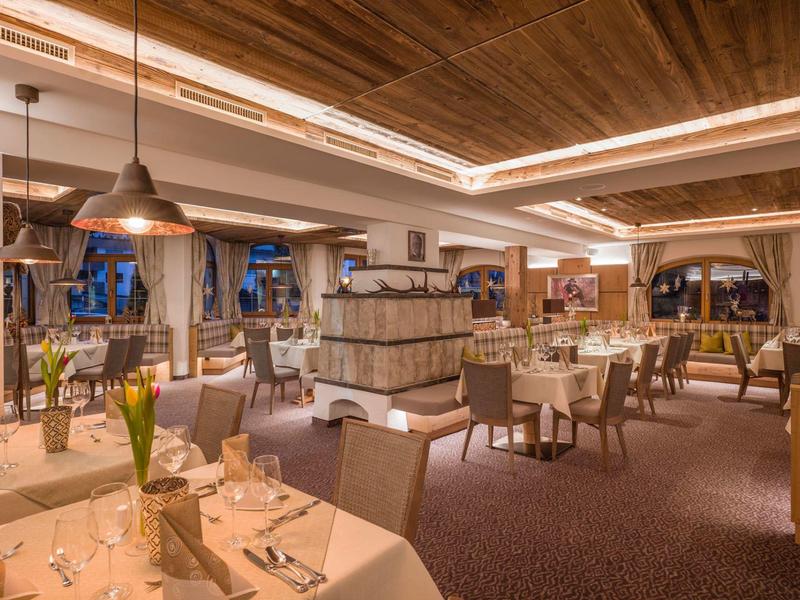 Interno elegante di un ristorante con tavoli apparecchiati, soffitto in legno e illuminazione accogliente