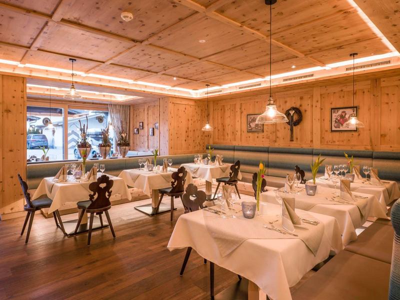 Sala da pranzo arredato con gusto, pareti in legno, tovaglie bianche e tavoli elegantemente apparecchiati.