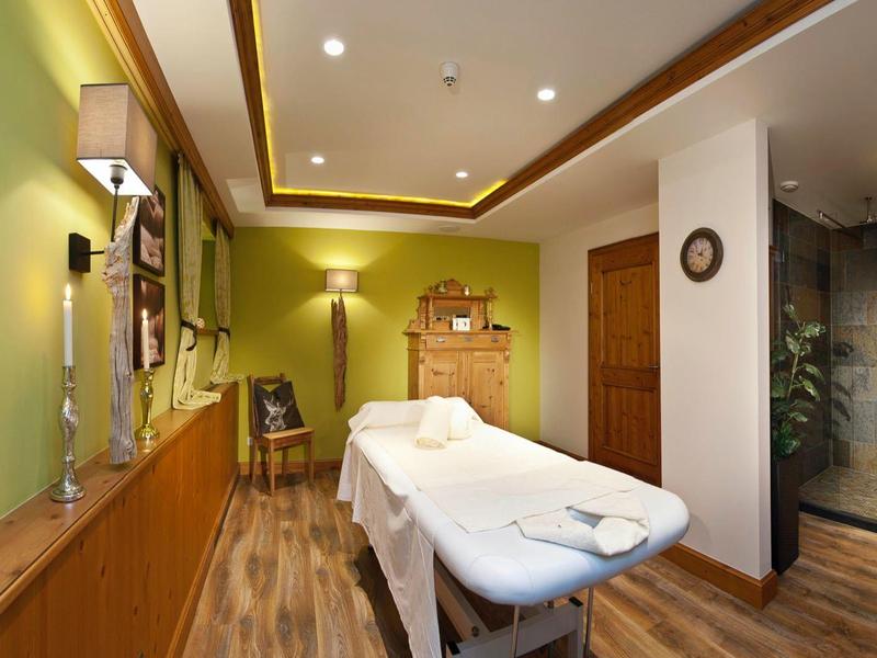 Sala trattamenti con lettino da massaggio, illuminazione calda e atmosfera rilassante.