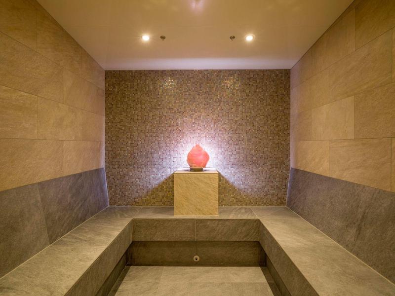 Sala spa moderna con parete a mosaico e vaso decorativo su un piedistallo