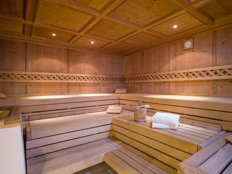 Sauna in legno accogliente con panchine a più livelli e illuminazione soffusa.