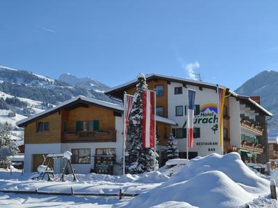 Schneebedecktes Hotelgebäude vor Bergkulisse mit sonnigem Himmel.