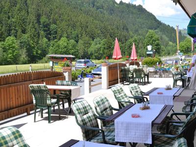 Terrazza con tavoli apparecchiati e sedie davanti a un paesaggio montano e foreste verdi