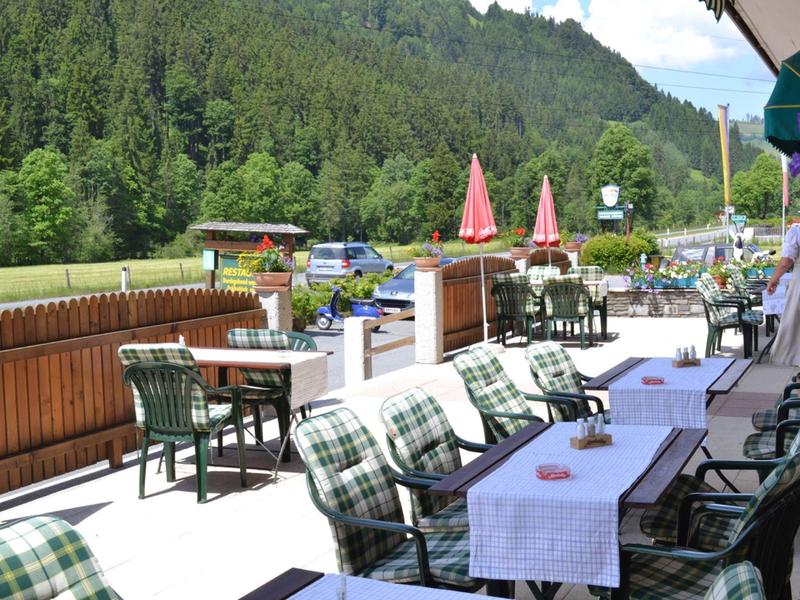 Taras restauracji z stołami, krzesłami i widokiem na zielone góry w tle