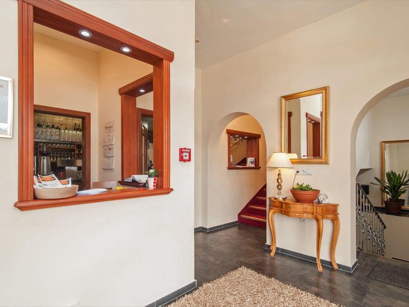Bright hallway with wooden furniture, carpet, and an open pass-through to a hotel bar or reception.