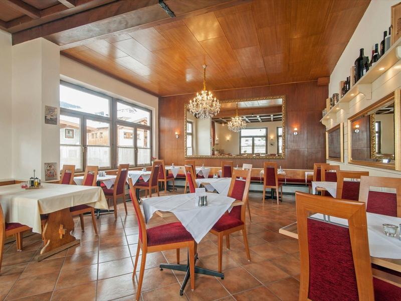 Elegant dining room with red chairs, white tablecloths, and chandeliers on the ceiling.
