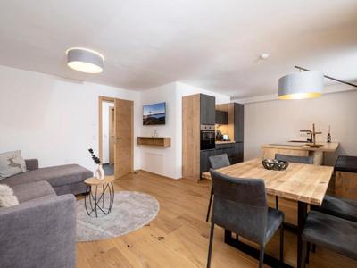 Moderner Wohn- und Essbereich mit grauem Sofa, Holztisch und dekorativem Teppichboden.