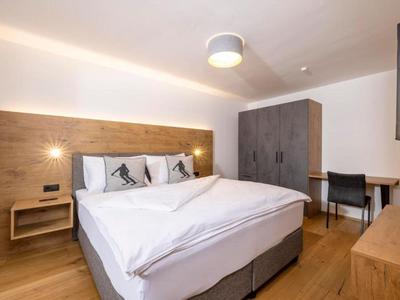 Modernes Hotelzimmer mit Doppelbett, Holzakzenten und einem Arbeitsplatz mit Stuhl.