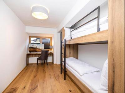 Schlichte Hotelzimmer mit Etagenbett, Schreibtisch und Fenster mit Blick auf Innenhof.