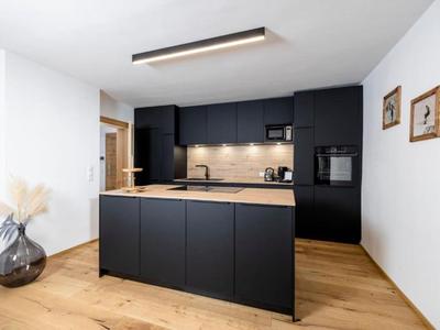 Moderne Hotelküche mit schwarzer Insel, Holzfußboden und minimalistischer Einrichtung.