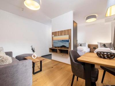 Moderner Wohnbereich mit Sofa, Esstisch, Stühlen und Wandspiegel in warmen Holztönen.