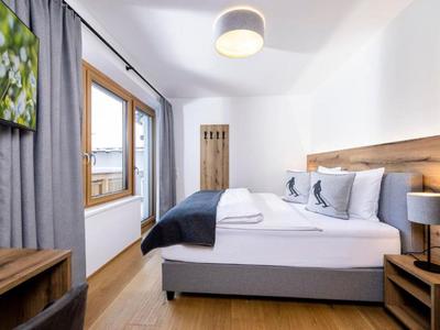 Modernes Hotelzimmer mit großem Doppelbett, Holzmöbeln und hellem Boden.